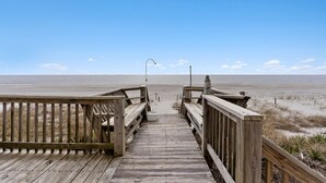 En träpromenad som leder till en strand med klar himmel.