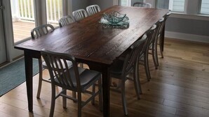 A dining area with a wooden table and chairs, large windows, and a view of the outdoors. - Best Day Ever 4 Bedroom Home by RedAwning (Supply)