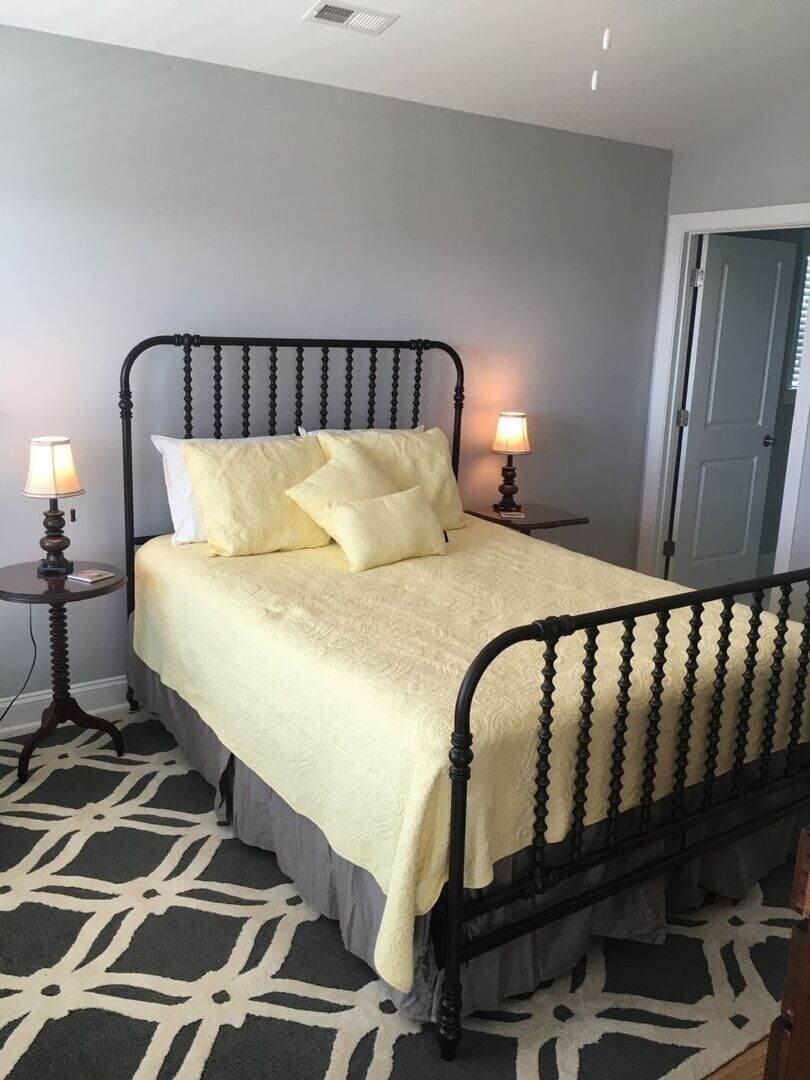 A bed with a headboard, two bedside tables with lamps, and a patterned rug.