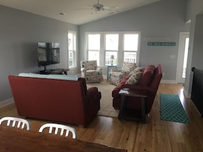 Ein Wohnzimmer mit einem roten Sofa, einem Fernseher und einem Deckenventilator.