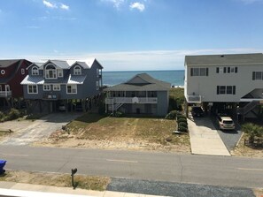 A residential area with houses, a road, and a beach in the background.