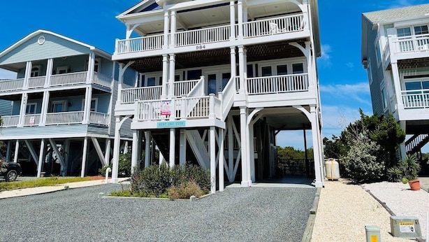 A multi-story beachfront property with a balcony, a covered entrance, and a clear sky. - Best Day Ever 4 Bedroom Home by RedAwning (Supply)