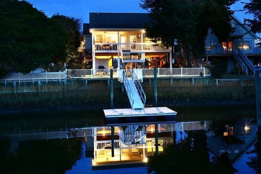 A waterfront property with a dock, a staircase leading to a deck, and a reflection in the water.