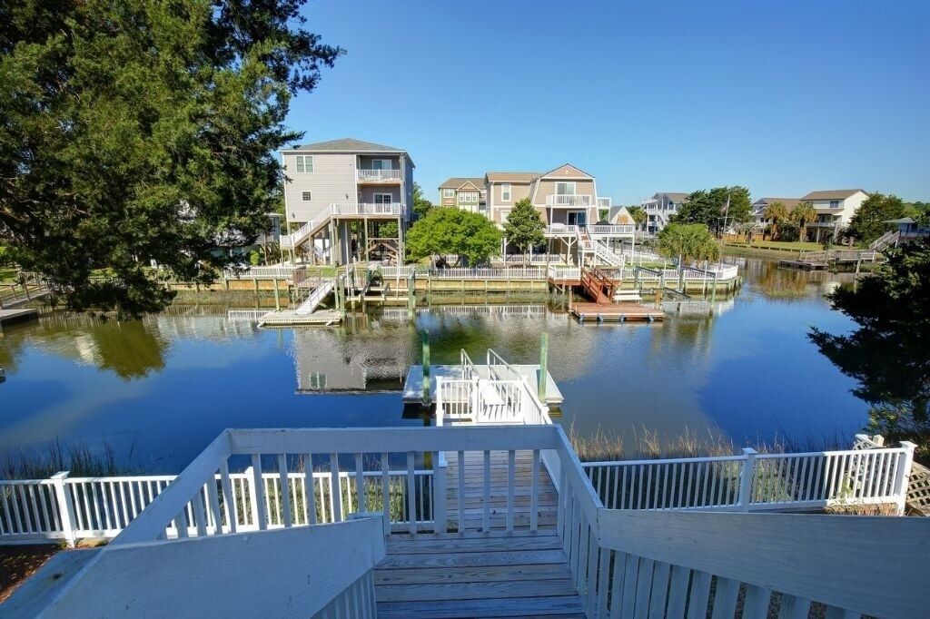 A waterfront property with a dock, a small boat, and a row of houses.