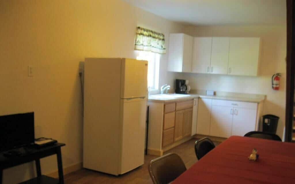 A compact kitchen with a refrigerator, a coffee maker, and cabinets.