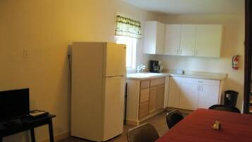 A compact kitchen with a refrigerator, a coffee maker, and cabinets.