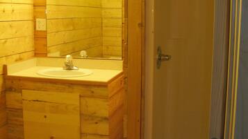 Un baño de madera con lavamanos y espejo, una puerta de ducha y un sello de fecha.
