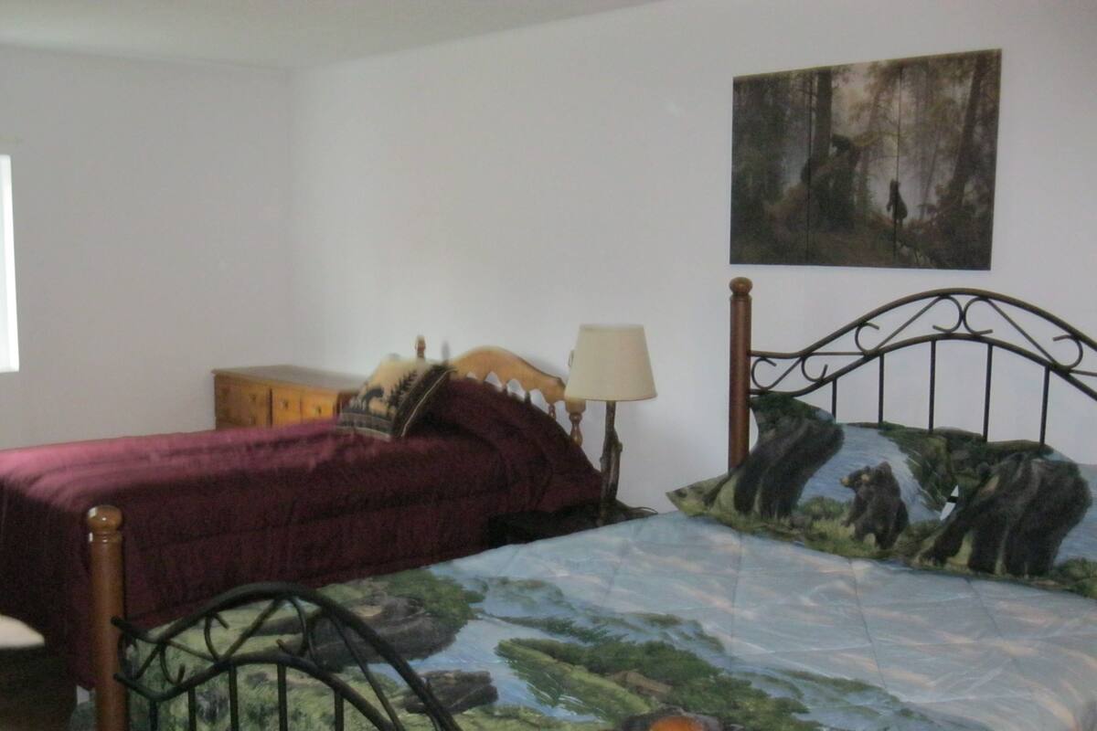 A bedroom with a bed, a nightstand, a lamp, a dresser, and a painting on the wall.