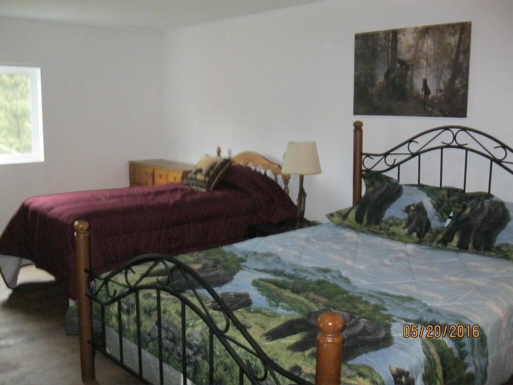 Una camera da letto con un letto, un comodino, una lampada e un quadro appeso al muro.