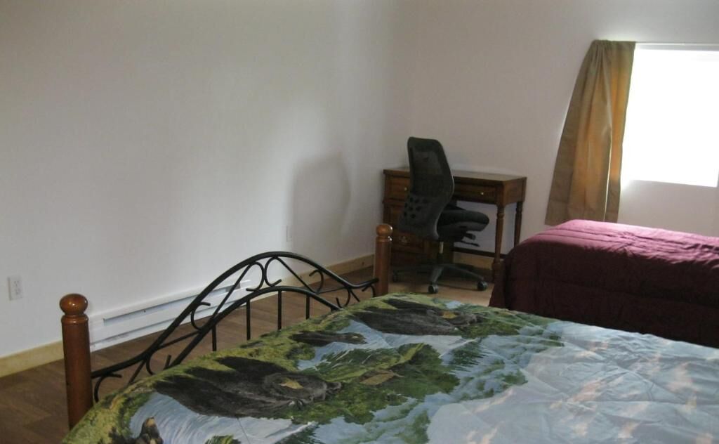 Un dormitorio con cama, escritorio y silla.