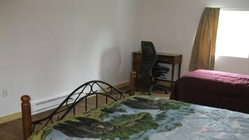 Un dormitorio con cama, escritorio y silla.