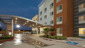 L’entrée d’un hôtel Fairfield Inn & Suites Marriott, avec un passage couvert, un parking et une place de stationnement réservée aux personnes handicapées.