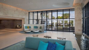 A spacious lobby with a modern sofa set, a round coffee table, and a small seating area with stools. - Zota Beach Resort (Longboat Key)