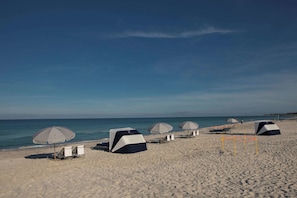 Relax on the beach with comfortable lounge chairs and umbrellas, offering a serene sea view.