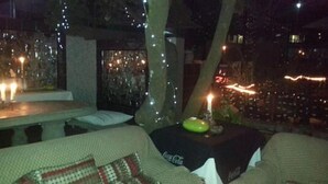 Een terras met een tafel en stoelen, versierd met lichtslingers en kaarsen.