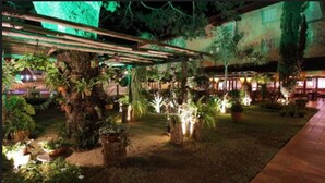 A courtyard with a pergola, potted plants, and a pathway. - Hotel Mantovani (Águas de Lindóia)