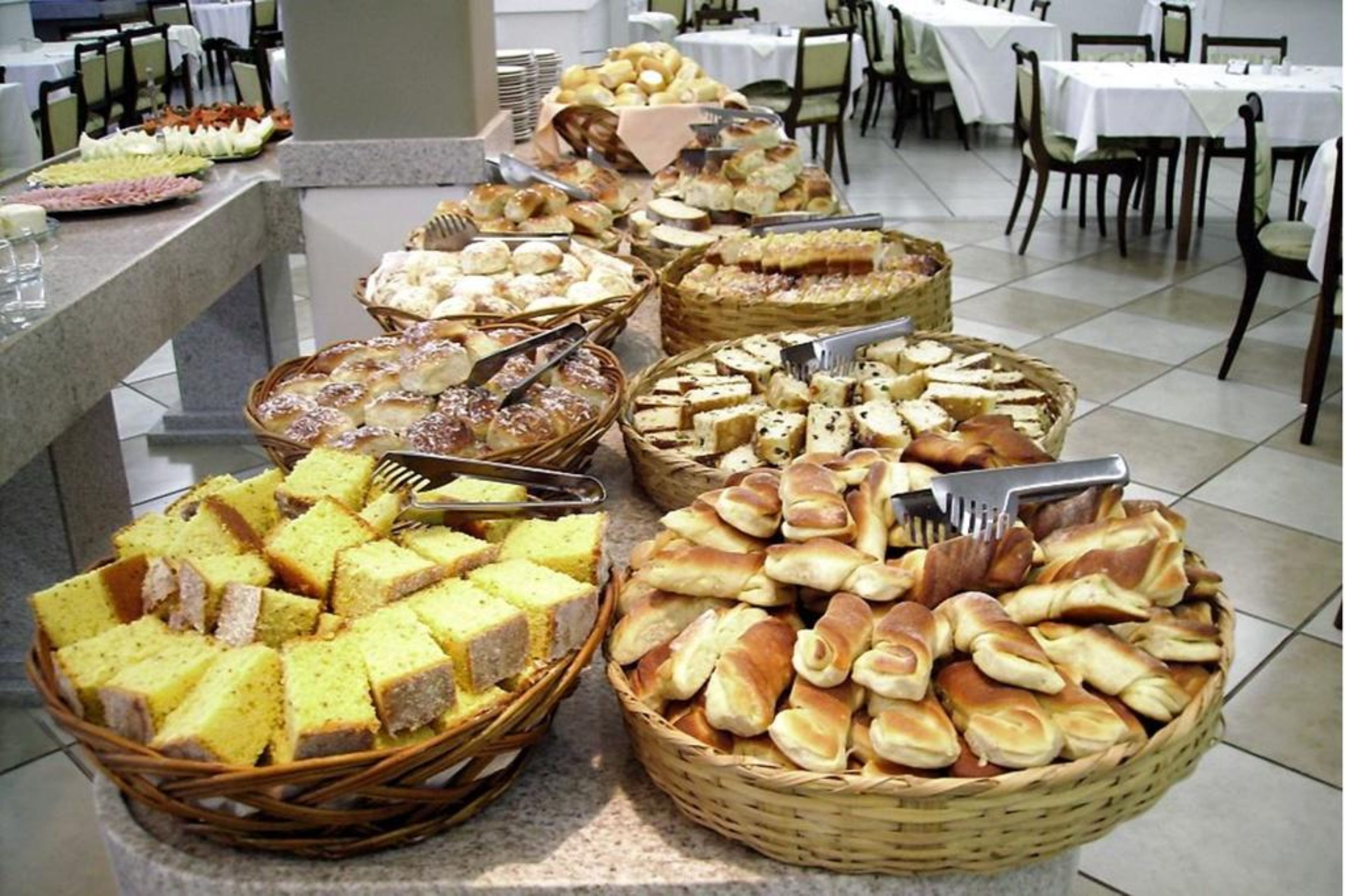 Um buffet com diversas opções de pães e doces.