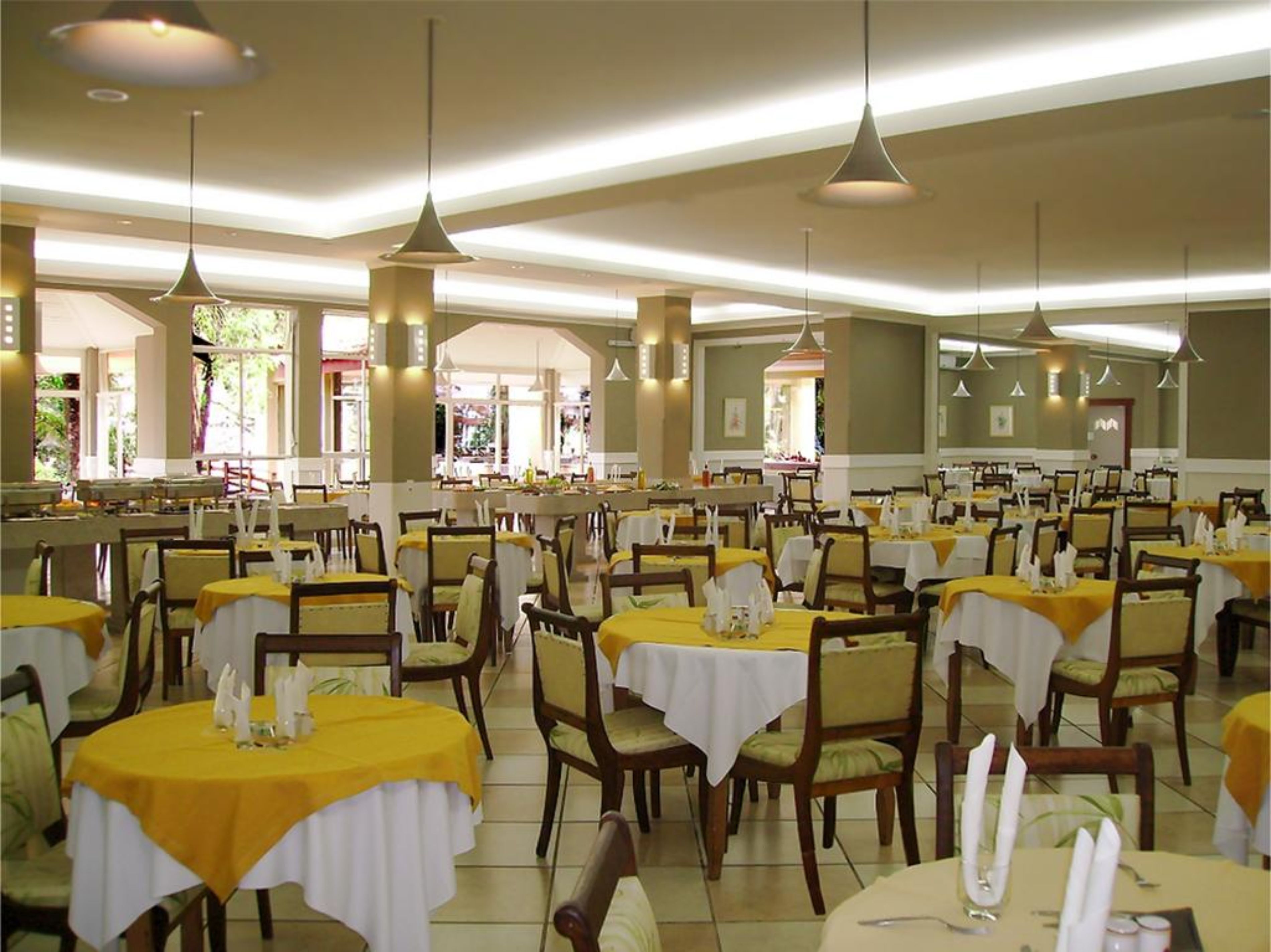 A large dining area with multiple tables, chairs, and pendant lights.