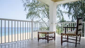 A covered balcony with a view of the beach and ocean.