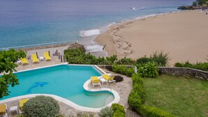 Una piscina con sillas amarillas y vista a la playa y al océano.