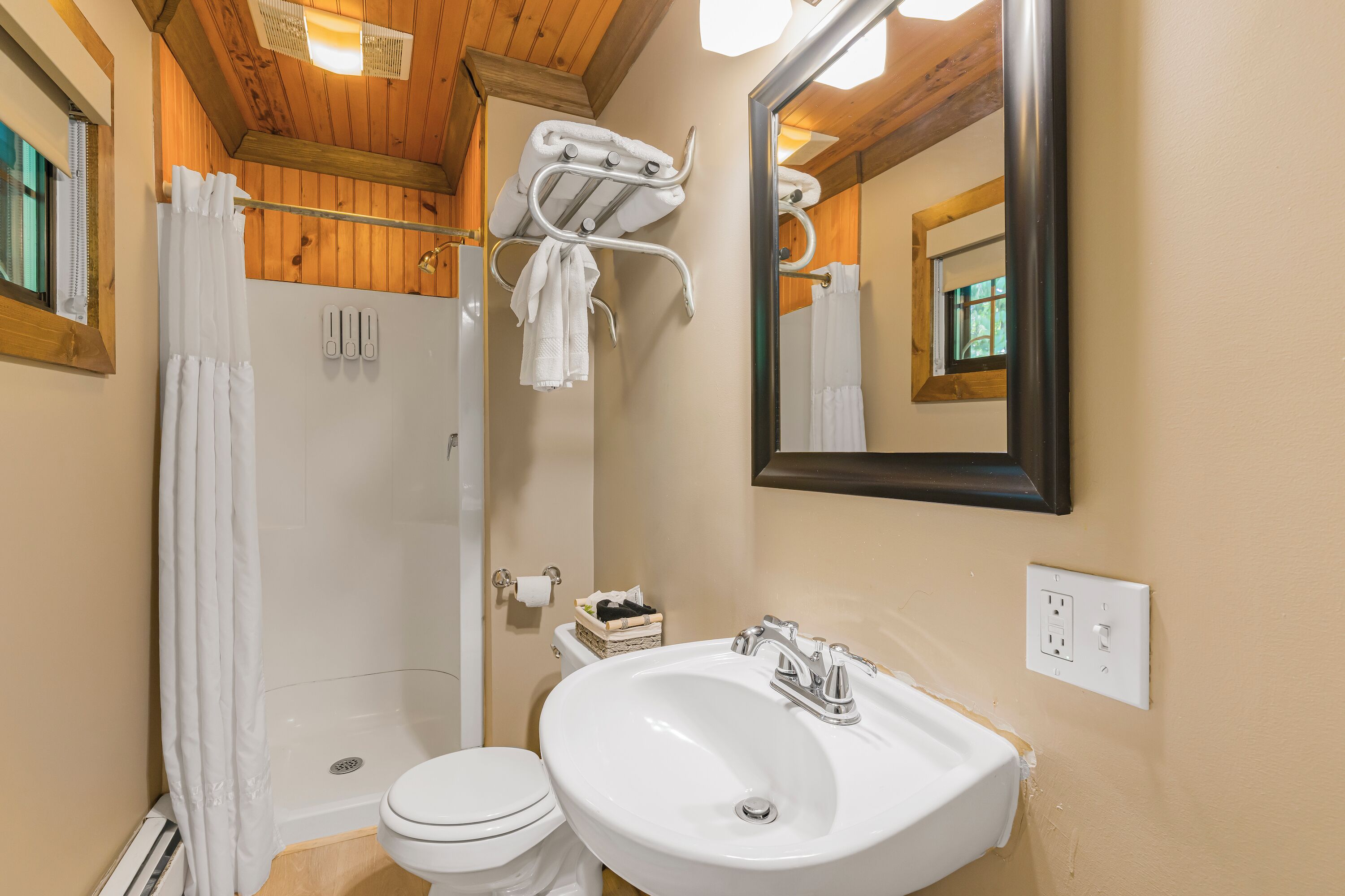 A bathroom with a shower, toilet, sink, and towel rack.