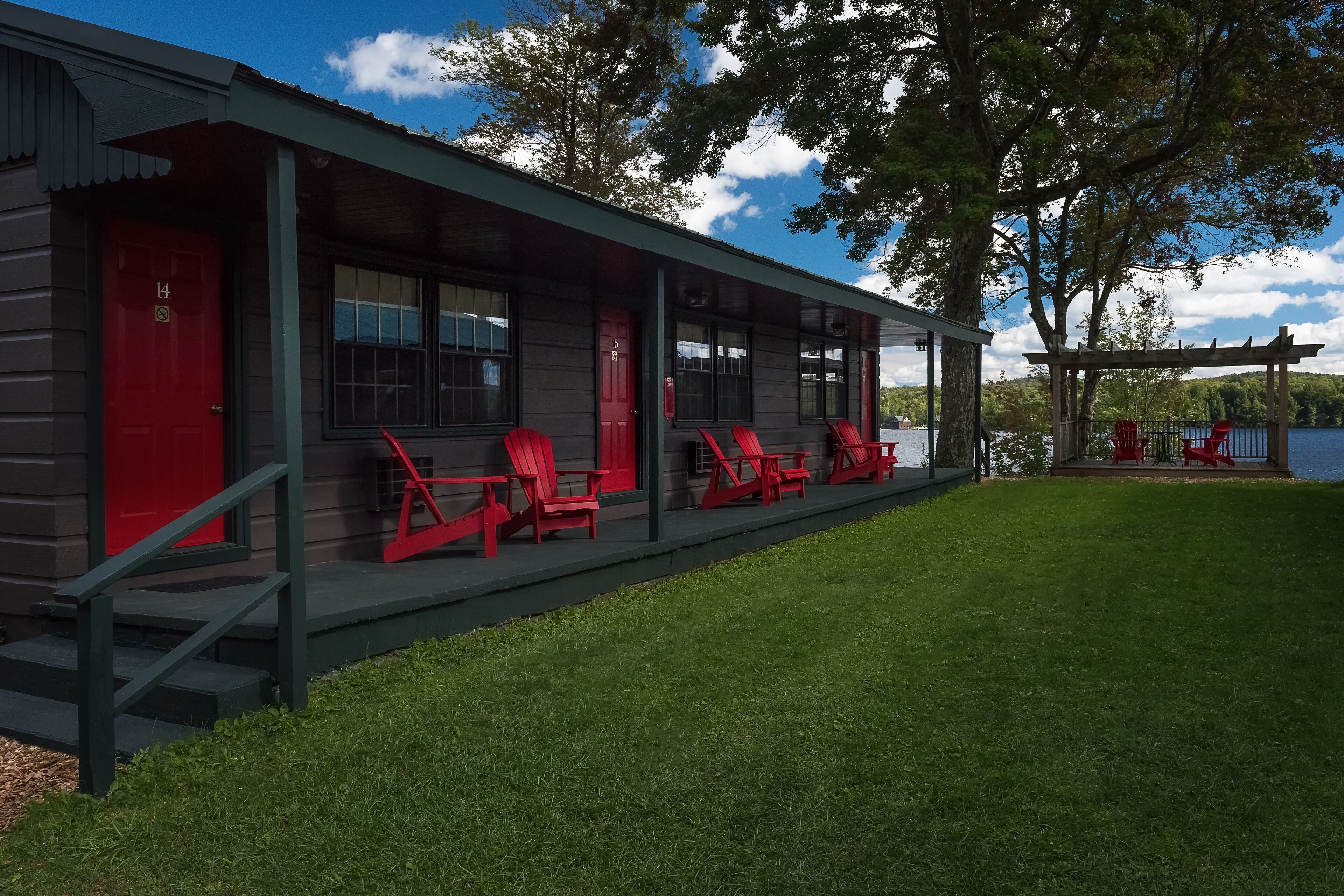 A lodge with a covered porch, red doors, and outdoor seating.