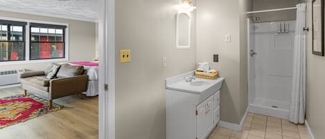 A modern bathroom with a shower, a sink with a basket, and a mirror.