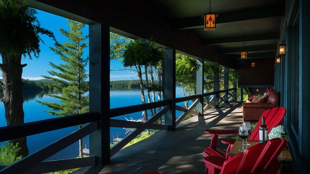 Un espacio de estar al aire libre techado, con vista a un lago y árboles.