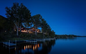 A lakeside lodge with a dock, surrounded by trees and a calm lake.