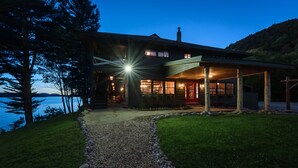 Una casa moderna con un porche cubierto, un camino de piedra y vista al agua.
