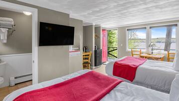 A hotel room with two beds, a TV, a balcony with a view, and a red door.