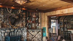 Un interior rústico con chimenea de piedra, mobiliario de cuero y techo de madera.