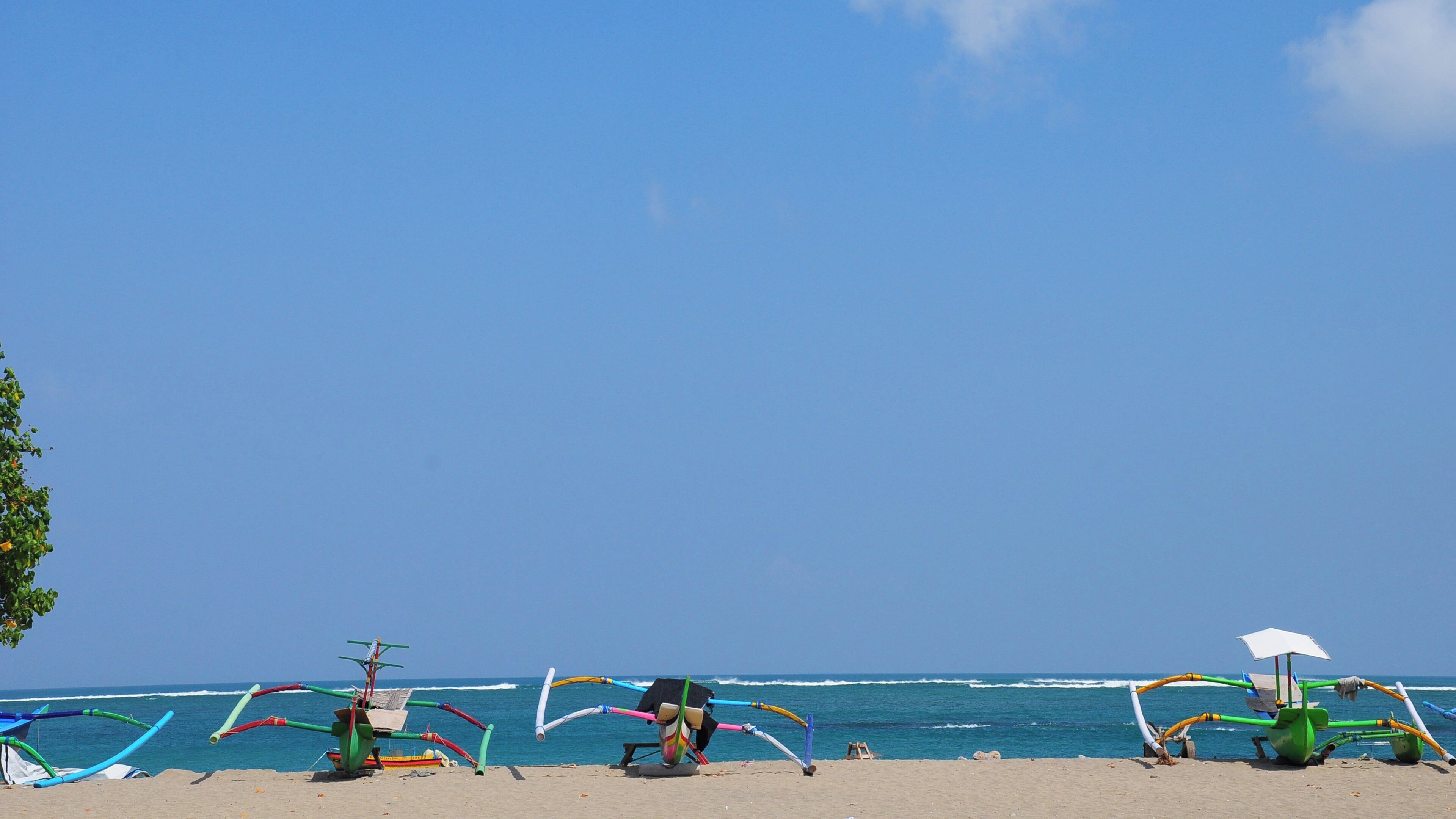 A beach with colorful kites and a small boat.