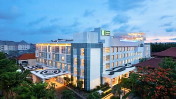 A modern hotel with multiple floors, a rooftop pool, and a landscaped garden.