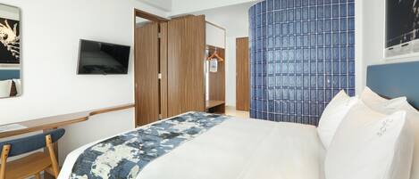 Ein Hotelzimmer mit Bett, Schreibtisch, Stuhl, Fernseher und Kleiderschrank.