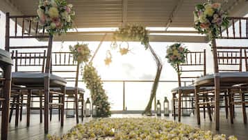 An aisle with chairs and a floral archway.
