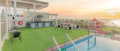 A rooftop bar with a pool, bar area, and seating.