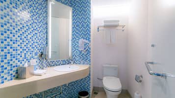 Een badkamer met een blauwe mozaïektegelwand, een witte wastafel, een spiegel, een toilet en een handgreep.