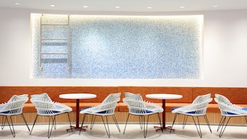 A modern interior with a seating area featuring white wicker chairs and a wooden bench.