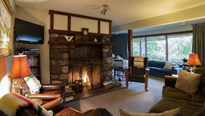 Una sala acogedora con chimenea de piedra, sillones de cuero, un sofá y un televisor.