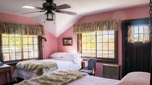 Habitación con dos camas, ventilador de techo y ventanas grandes con cortinas.