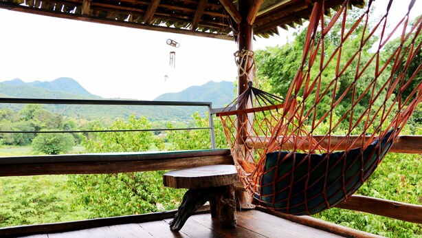A hammock chair with a view of a lush green landscape and mountains in the background. - UP2U Guesthouse - Hostel (Pai)