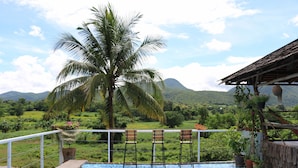 A balcony with a patterned floor, chairs, and potted plants. - UP2U Guesthouse - Hostel (Pai)