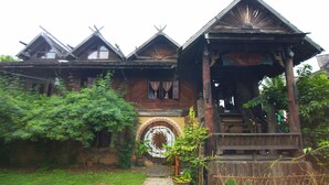 A traditional wooden house with a central circular door, surrounded by lush greenery. - UP2U Guesthouse - Hostel (Pai)