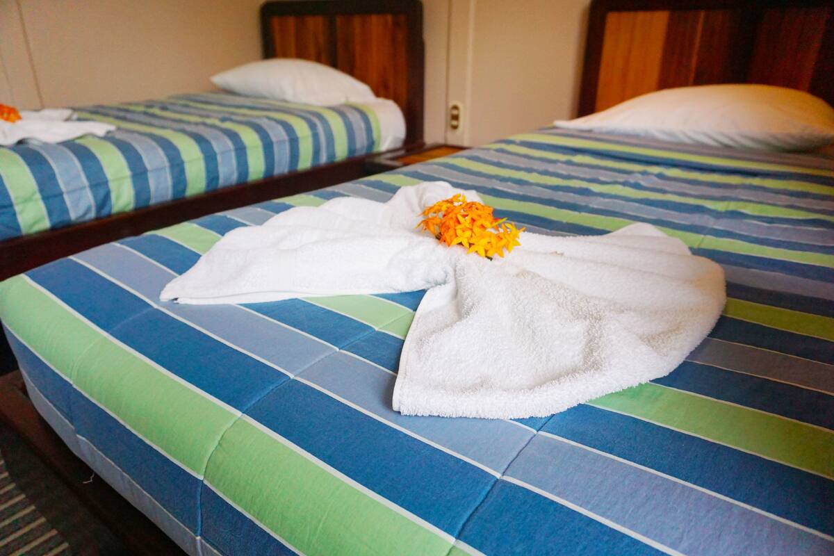 Ein Hotelzimmer mit zwei Betten, jeweils mit gestreifter Bettwäsche.