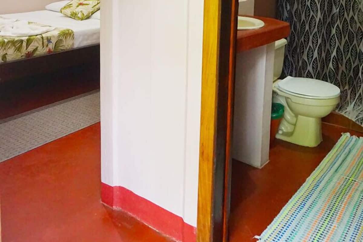 Ein kleines Zimmer mit Bett, Toilette und Duschbereich.
