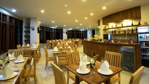 Un restaurante con mesas y sillas de madera, una zona de bar con estantes llenos de botellas, y una pantalla de televisión mostrando 'CHANGHONG'.