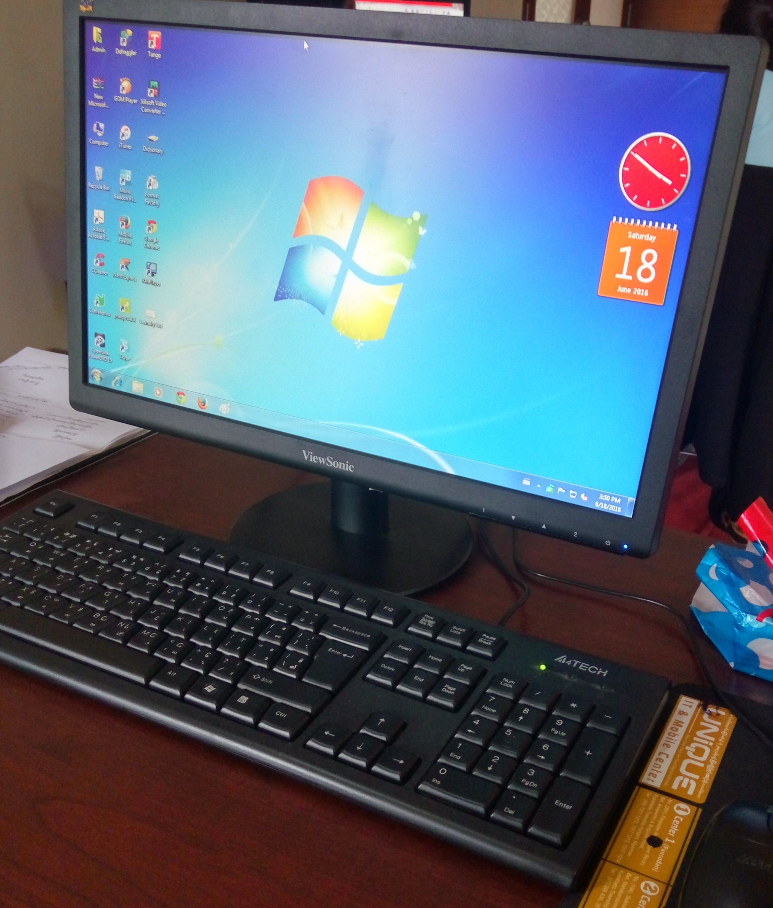 A desktop computer with a ViewSonic monitor and a black keyboard on a wooden desk.
