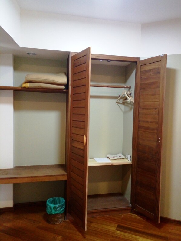 A walk-in closet with wooden doors, shelves, and a hanging rod.