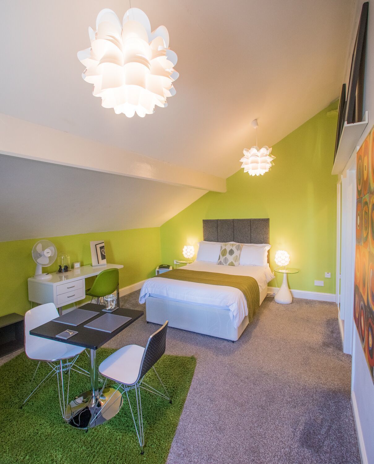 Un dormitorio moderno con cama, mesitas de noche, un escritorio y una silla.